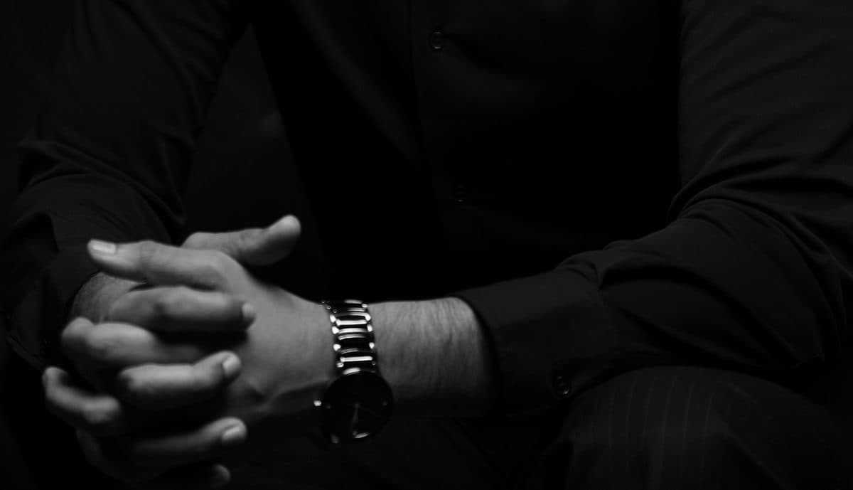 Hands clasped, resting.