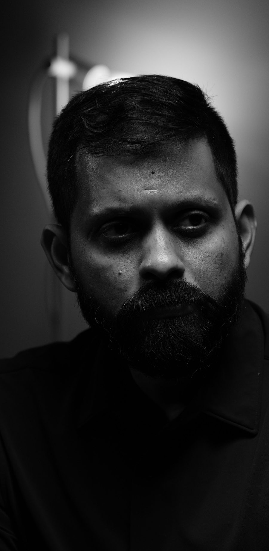 Shashank on a dark sofa, the seat beside him empty.