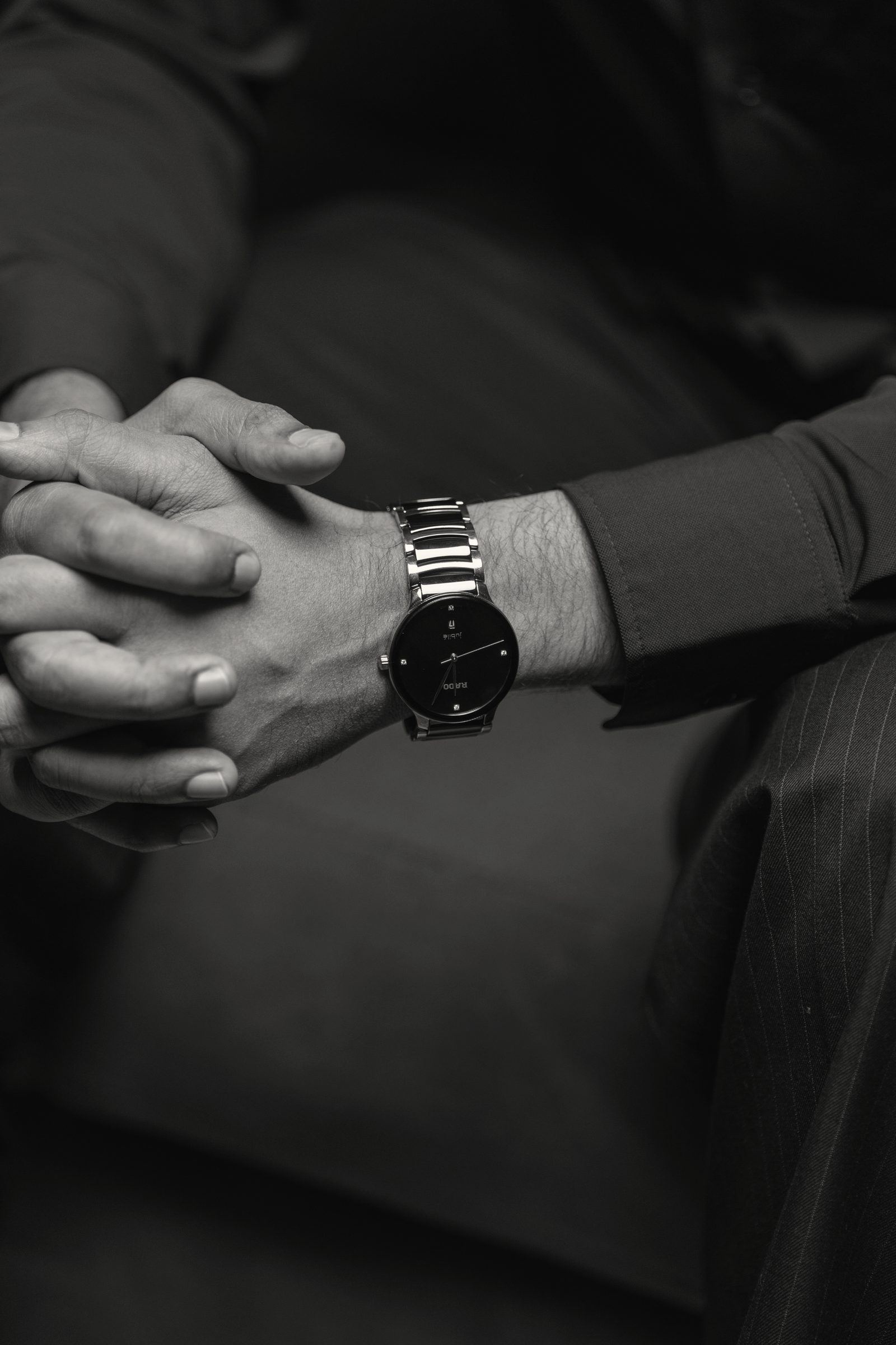 His hands, resting, a watch on the wrist.